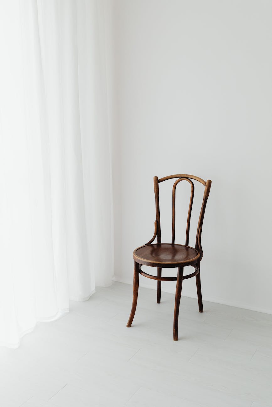 brown wooden chair beside white curtain